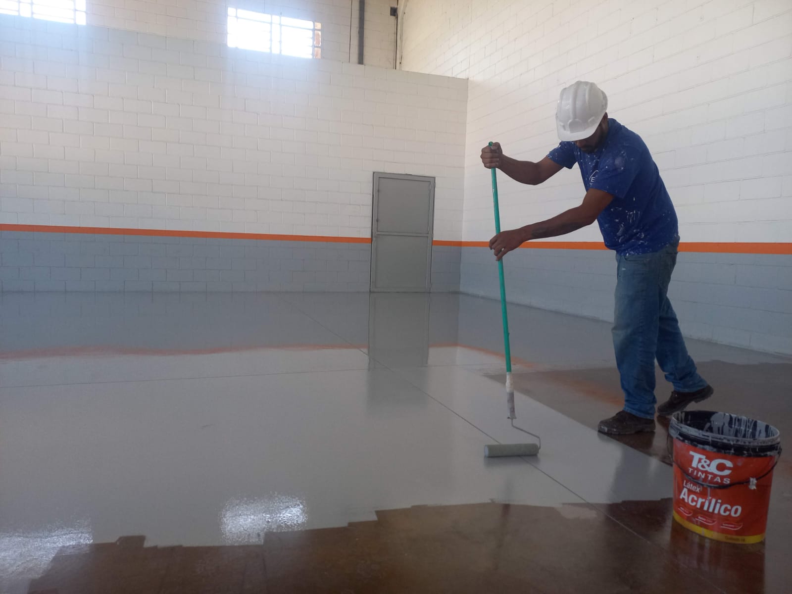Aplicação de tinta em piso de galpão